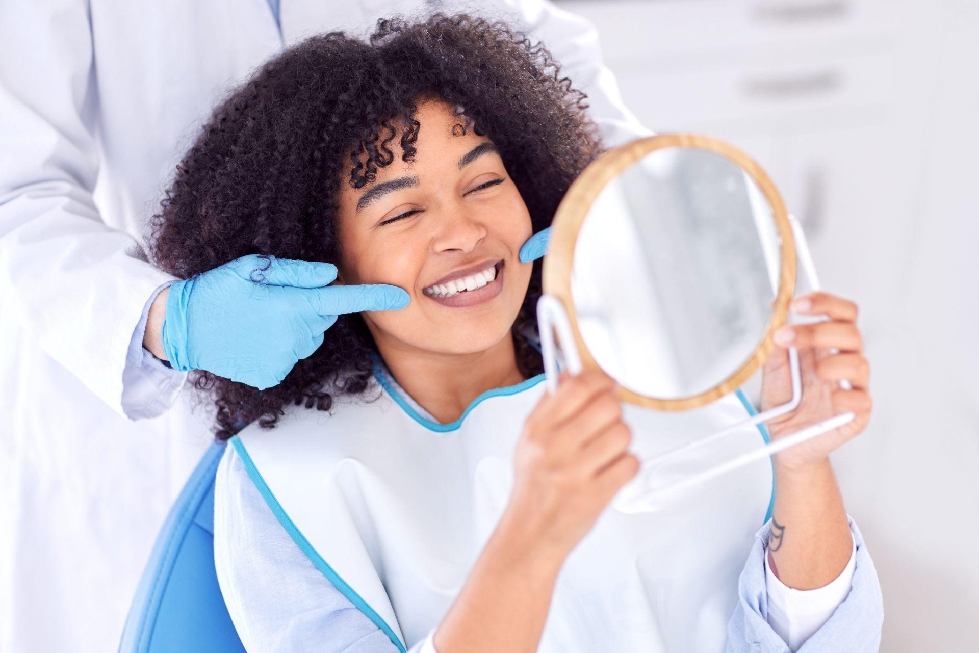Woman holding a mirror during a dental exam | Oral Health Niagara Falls